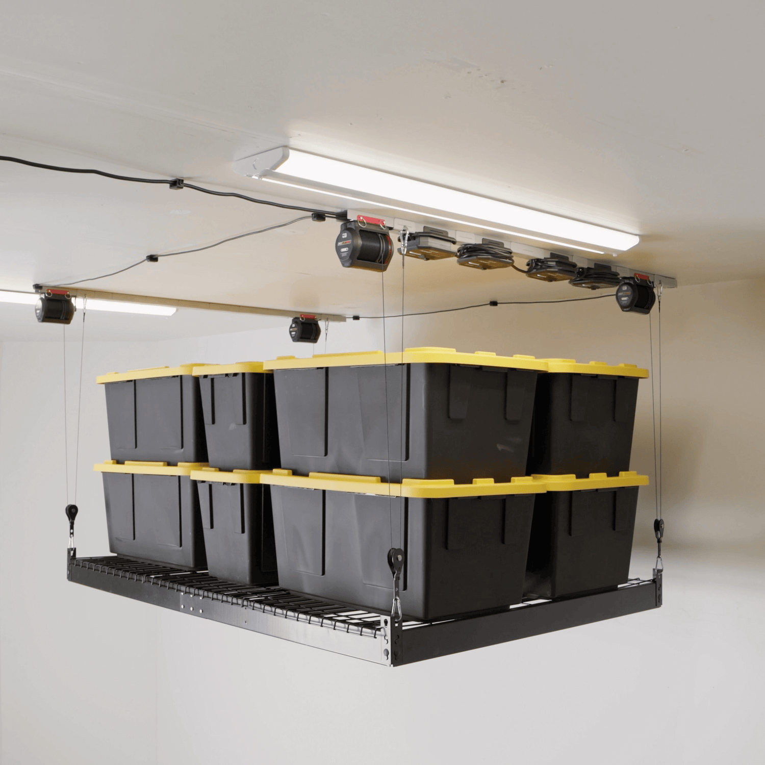 Overhead storage system with black containers and yellow lids hanging in a garage. 