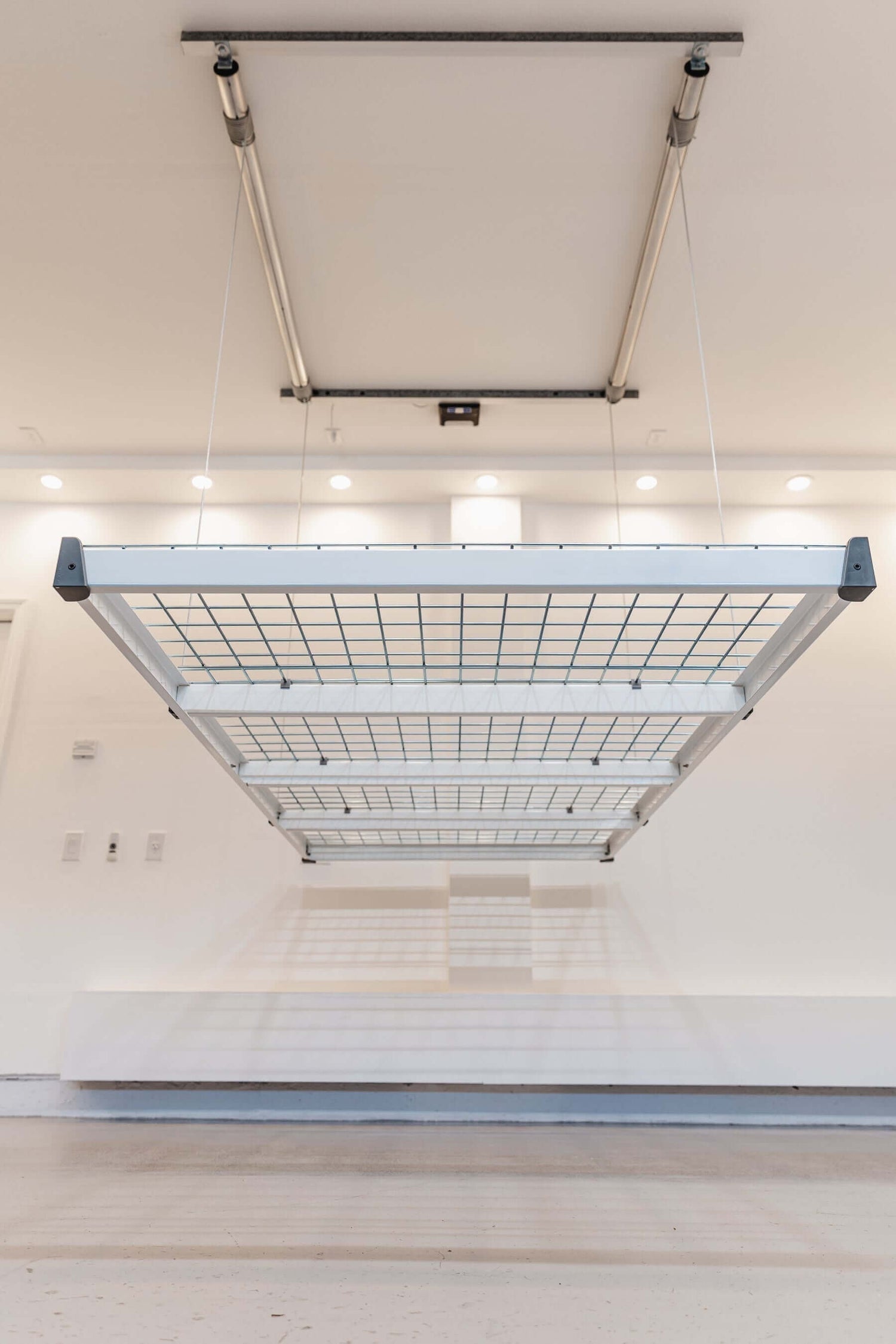 Garage storage lift system hanging from the ceiling, designed for efficient vertical storage of bulky items. 