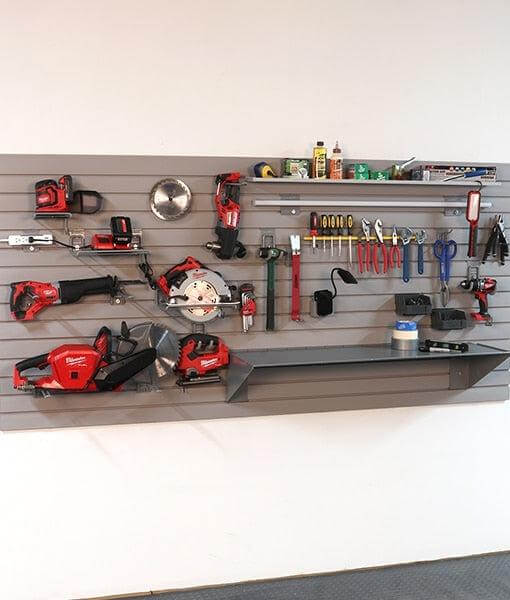Organized garage wall storage with various tools, including saws, drills, and a shelf for accessories. 