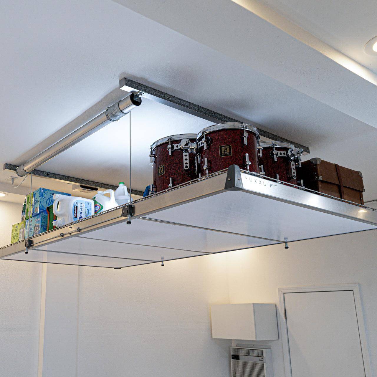 Auxx Lift accessory showcasing semi-transparent cover holding drums and boxes, demonstrating innovative storage solution.