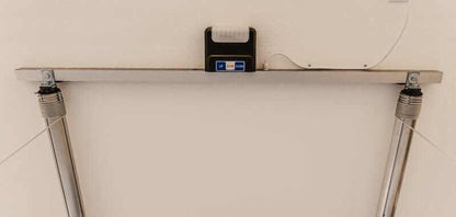 Auxx Lift motorized garage storage lift showing platform and control mechanism mounted on a wall.