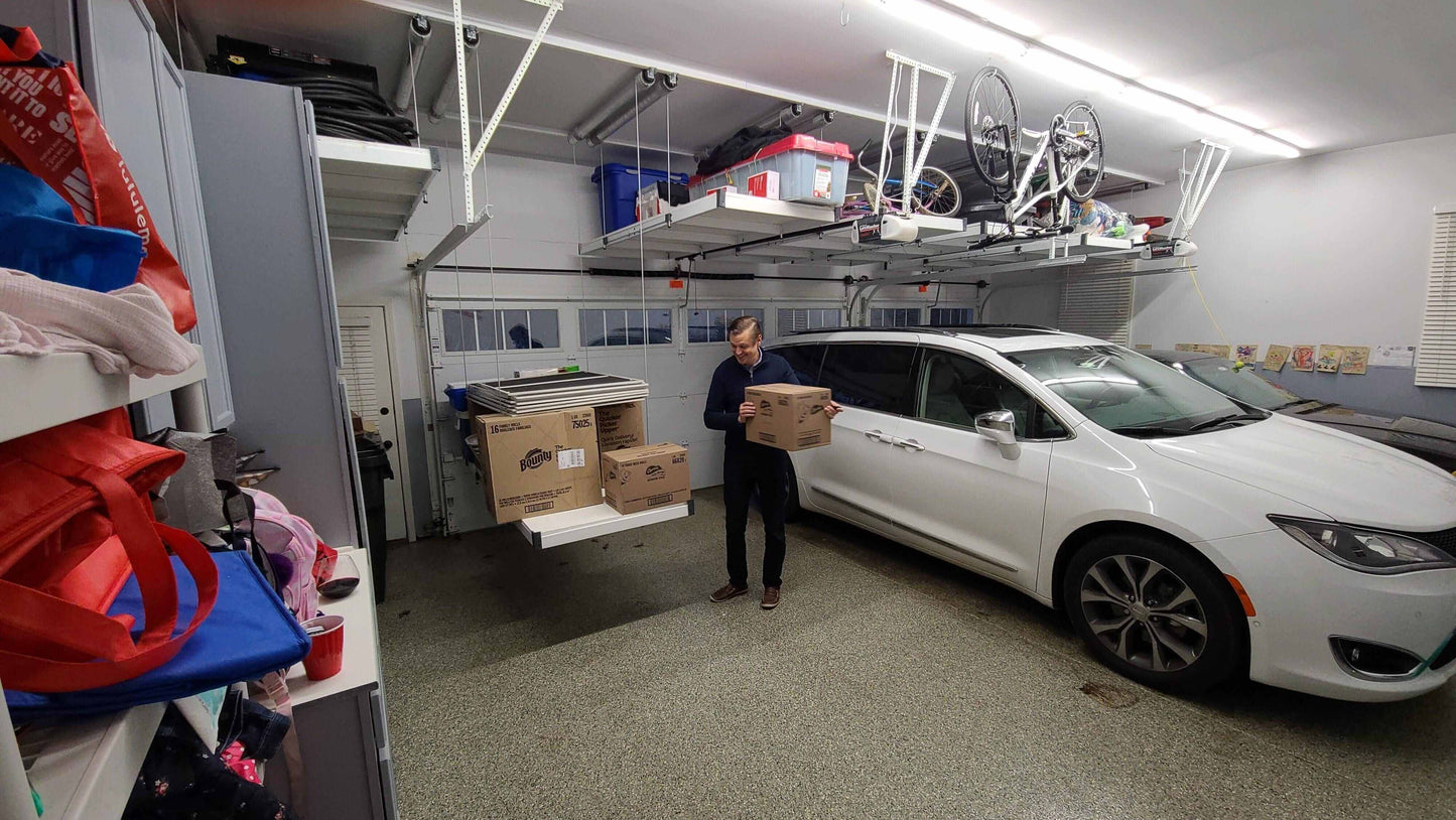 Person using Auxx Lift in garage to elevate boxes, showcasing a motorized garage storage lift for easy organization.