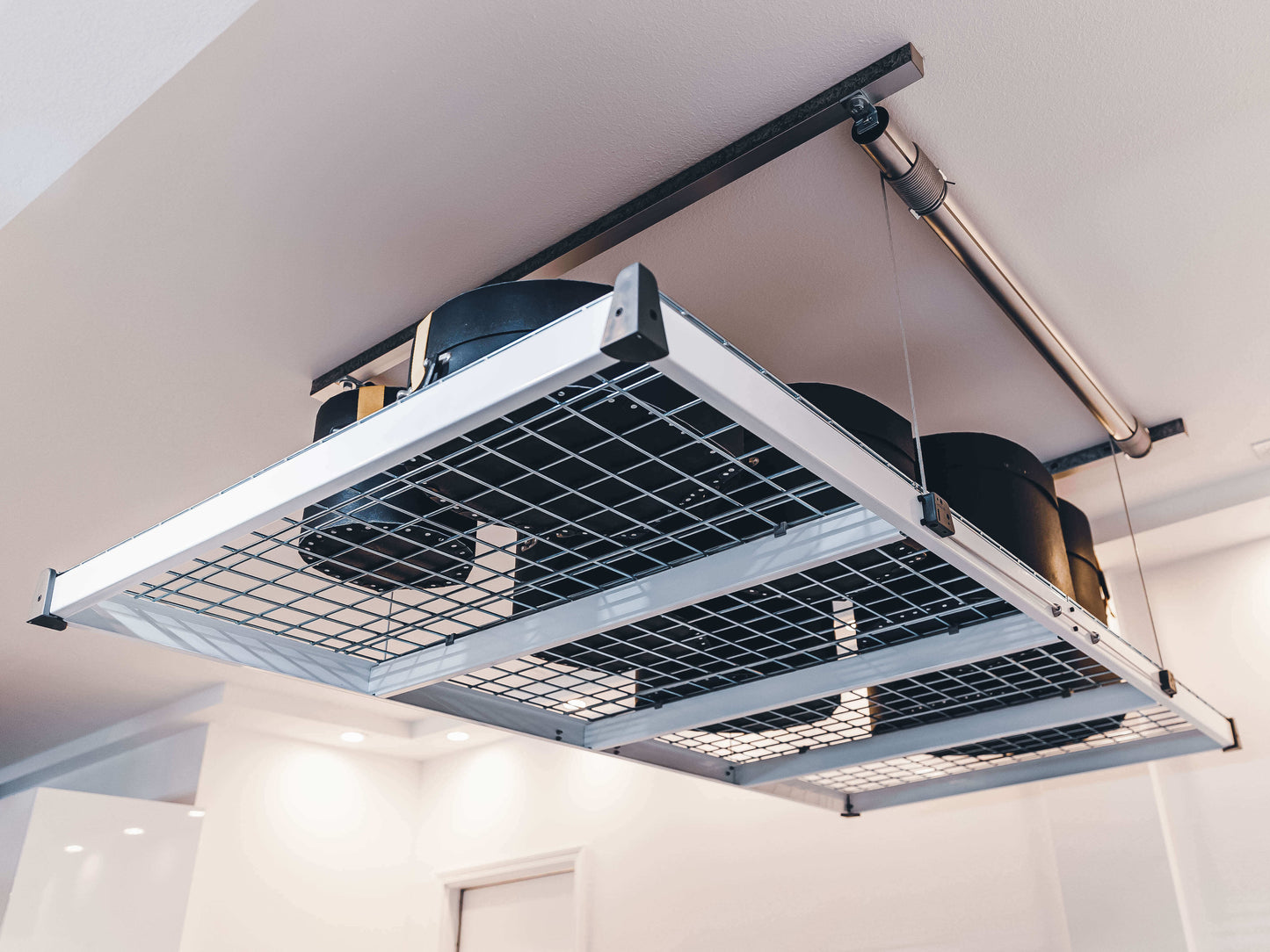 Auxx Lift motorized garage storage lift holding storage containers overhead in modern garage.