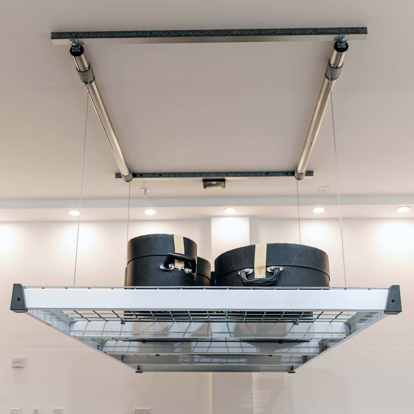 Auxx Lift motorized garage storage lift with elevated storage boxes against a modern ceiling.