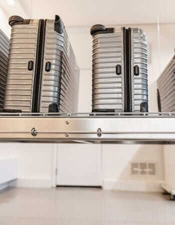 Sleek silver suitcases neatly arranged on an elevated storage platform in a modern interior.