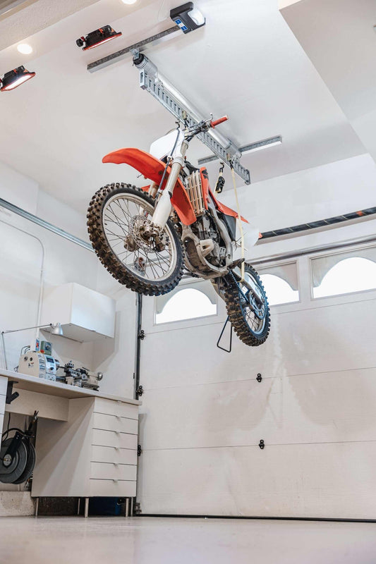 Motorcycle hoisted above garage floor using Auxx-One motorized garage storage lift.