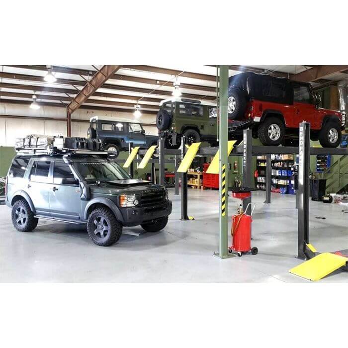 BendPak HD-9 four-post car lift in a garage with vehicles lifted, showcasing durable engineering.