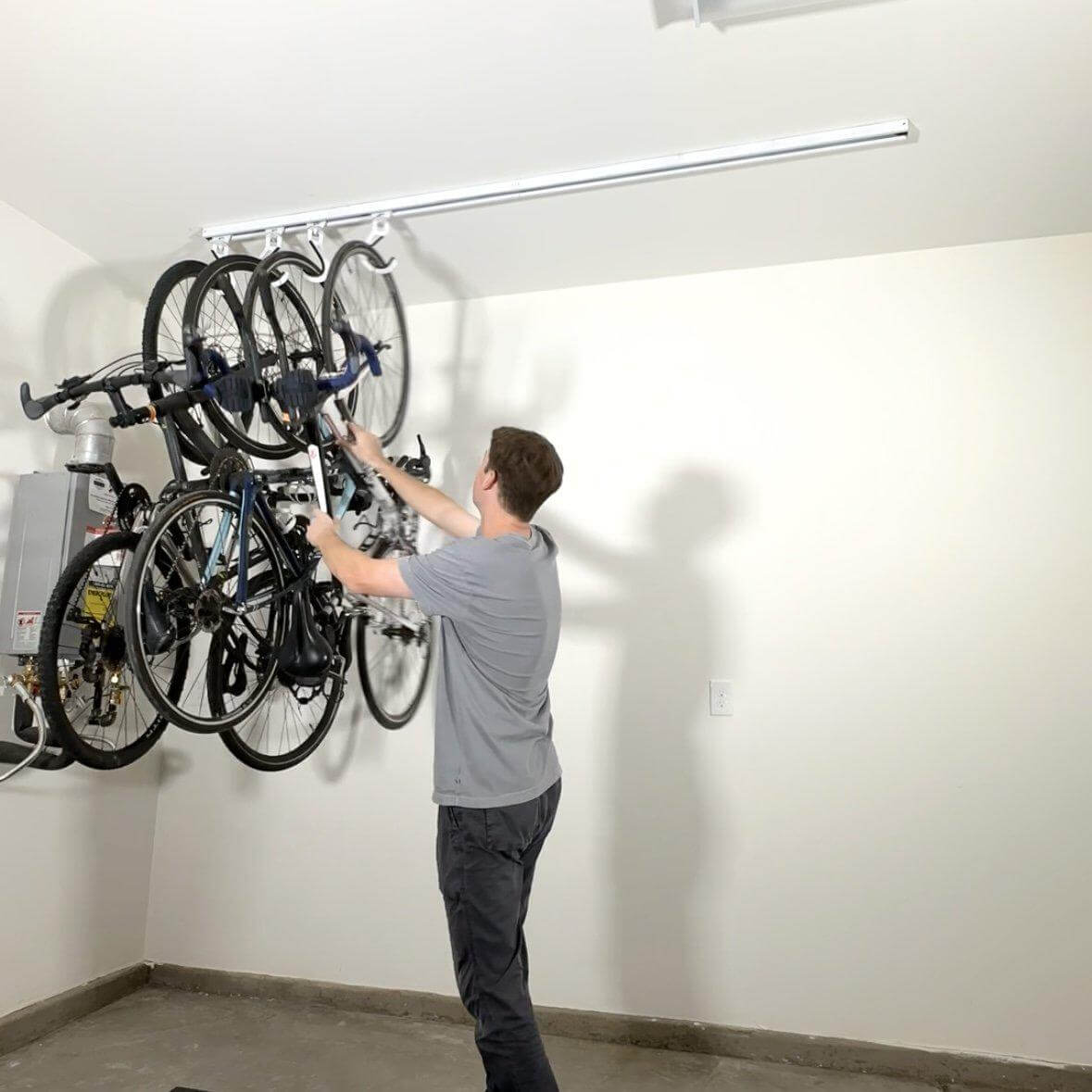 Man organizing four bikes on the Ceiling SAM Bike Slide Pro in a garage.