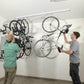 Men installing Ceiling SAM Bike Slide Pro to organize 4 bikes in a garage, showcasing DIY bike storage solution.