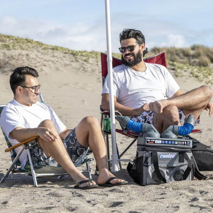 Two men relax on the beach with the Cool Boss Coolee CL-240, enjoying a cool breeze and refreshments.