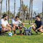 Three friends enjoying a day outdoors with the Cool Boss Coolee CL-240 air cooler and soccer ball in a park setting.