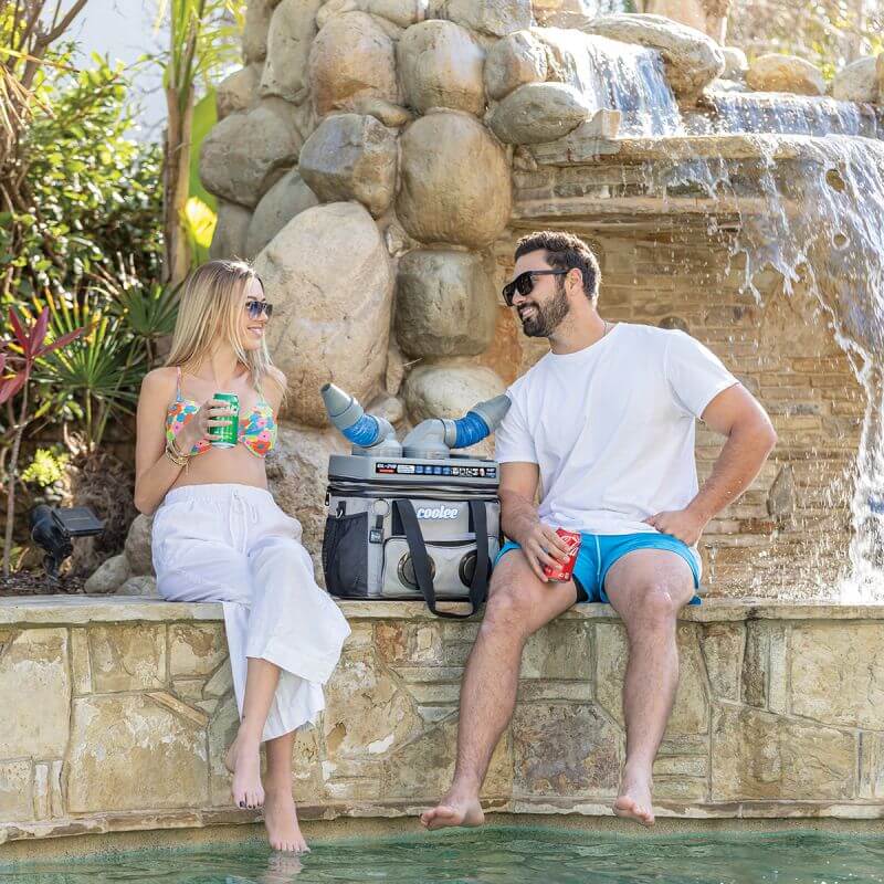 Couple enjoying drinks by a waterfall with the Cool Boss CL-240 Coolee 3-in-1 air cooler and Bluetooth player.