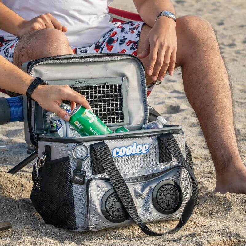 Person using the Cool Boss Coolee CL-240, a 3-in-1 air cooler, ice-chest, and Bluetooth player at the beach.