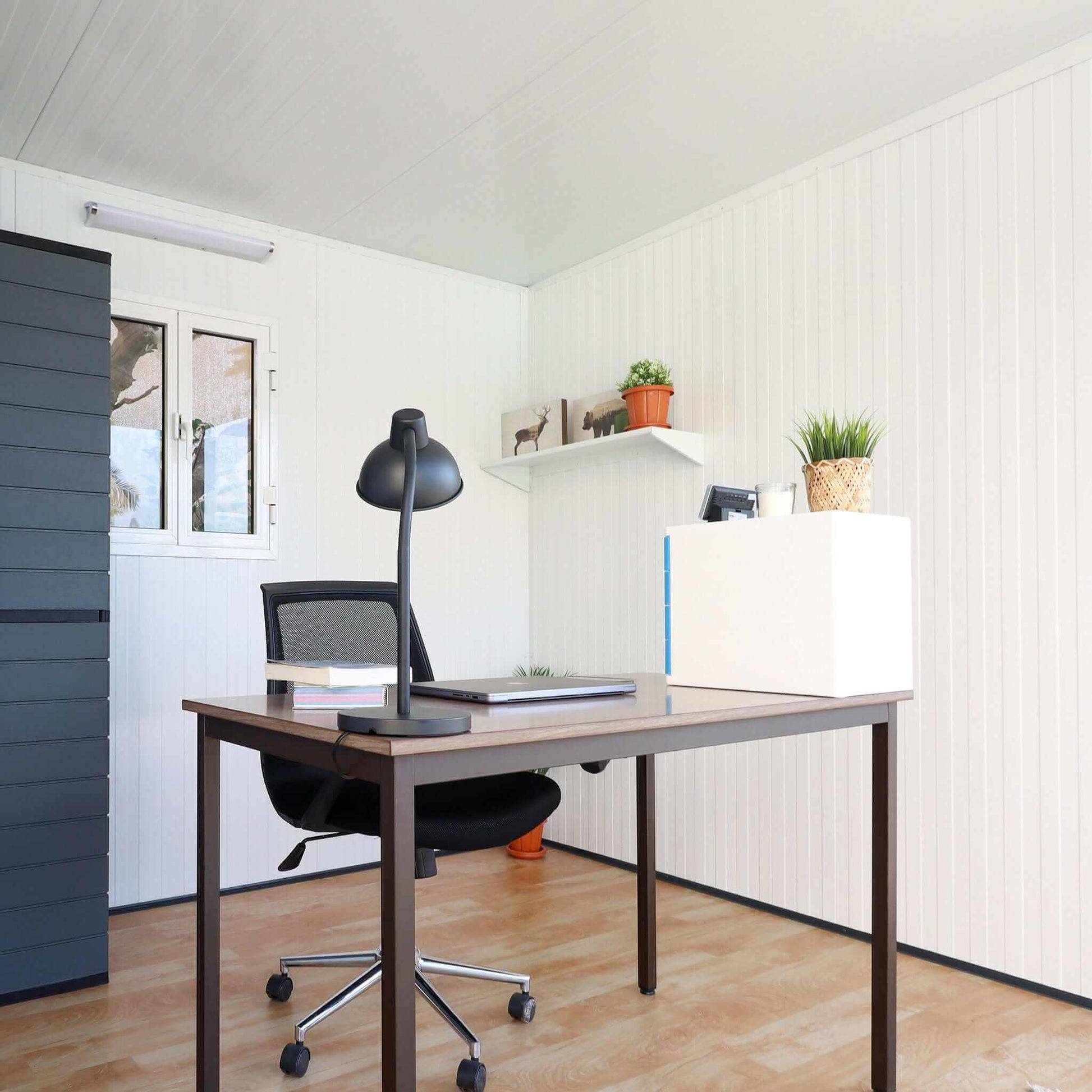 Modern office setup inside a Duramax 10x10 Garden Room with desk, chair, and plants.