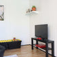 Interior view of a Duramax 10x10 Glass Garden Room with a TV, play area, and potted plant.