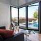 Interior view of a stylish 10x10 glass garden room with a cozy seating area and scenic pool view.