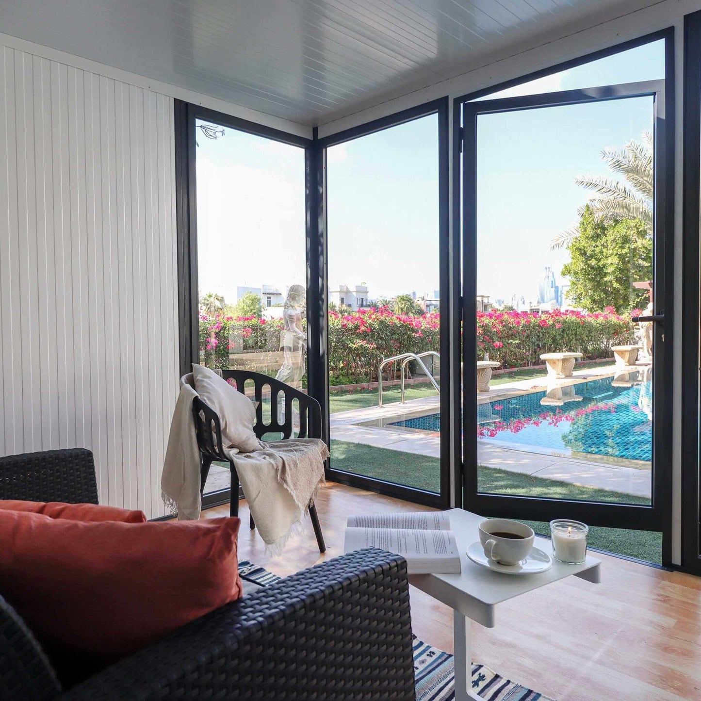 Interior view of a stylish 10x10 glass garden room with a cozy seating area and scenic pool view.