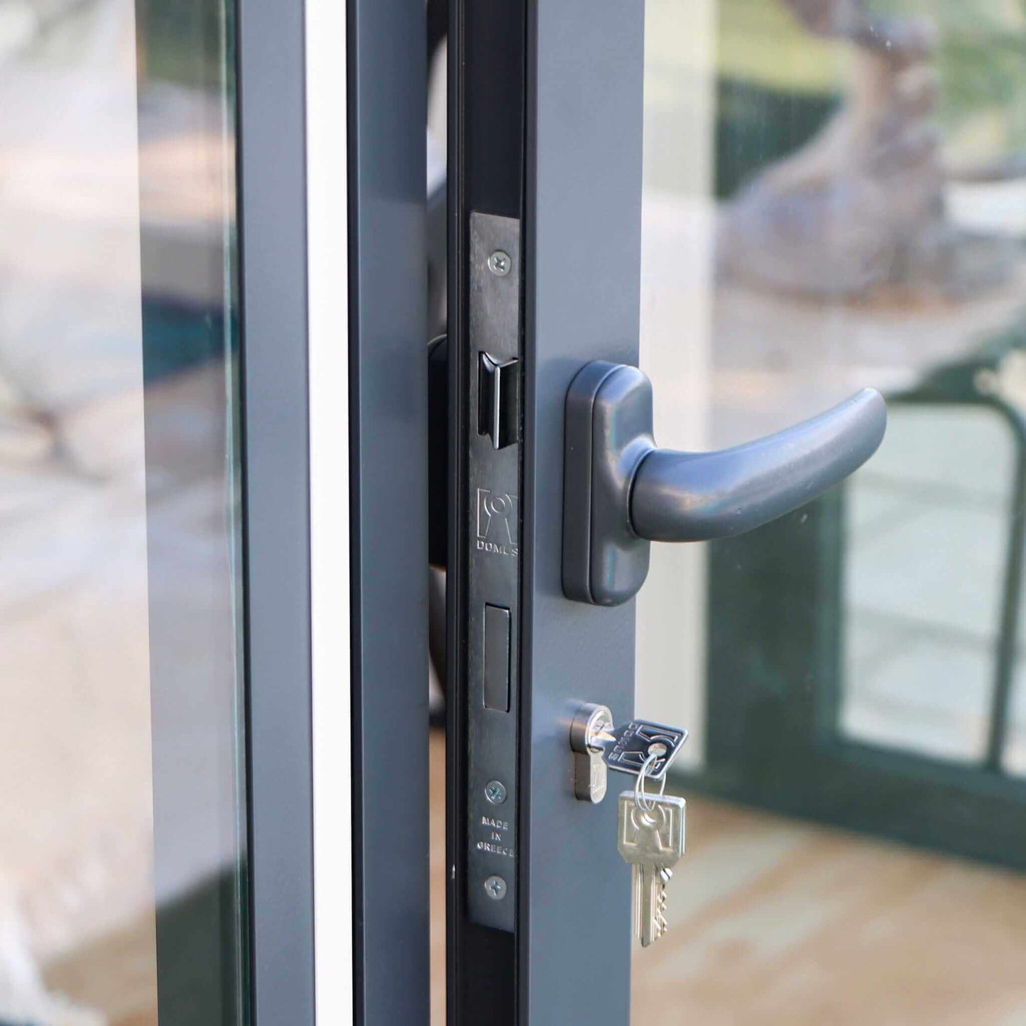 Duramax 10x10 Glass Garden Room door handle and lock detail with key, showcasing security features.