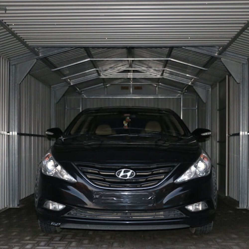 Black Hyundai sedan parked in a Duramax 12x20 Imperial Metal Garage with an industrial interior.