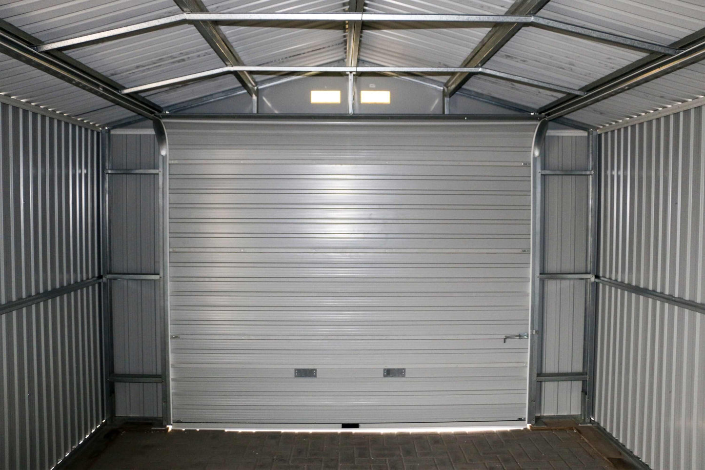 Interior view of a Duramax 12x20 Imperial Metal Garage showcasing light gray walls and large metal garage door.