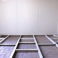 Interior view of a Duramax insulated building foundation with a gable roof and metal framing on a paved floor.