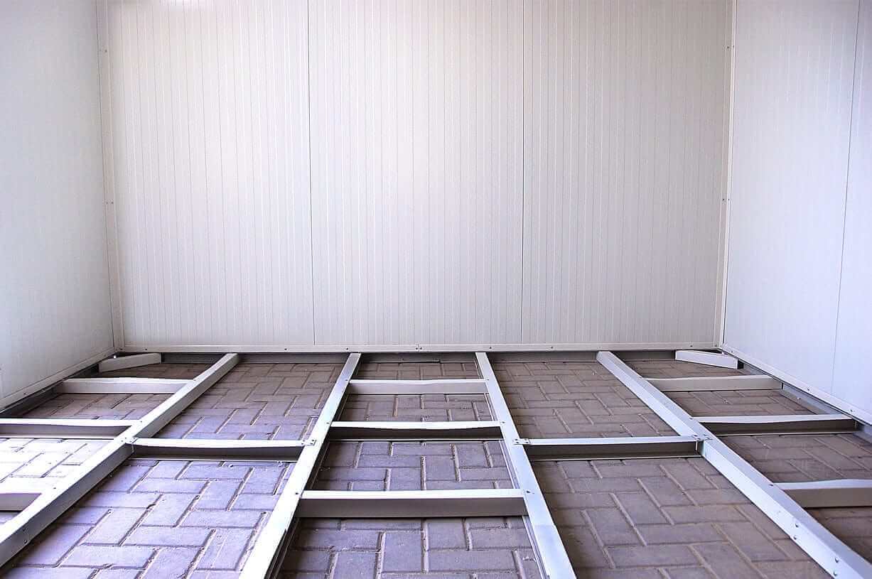 Interior view of a Duramax insulated building foundation with a gable roof and metal framing on a paved floor.