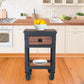 Rolling industrial workbench with drawer and shelf in a kitchen, styled with fruit and plates, showcasing functionality and design.