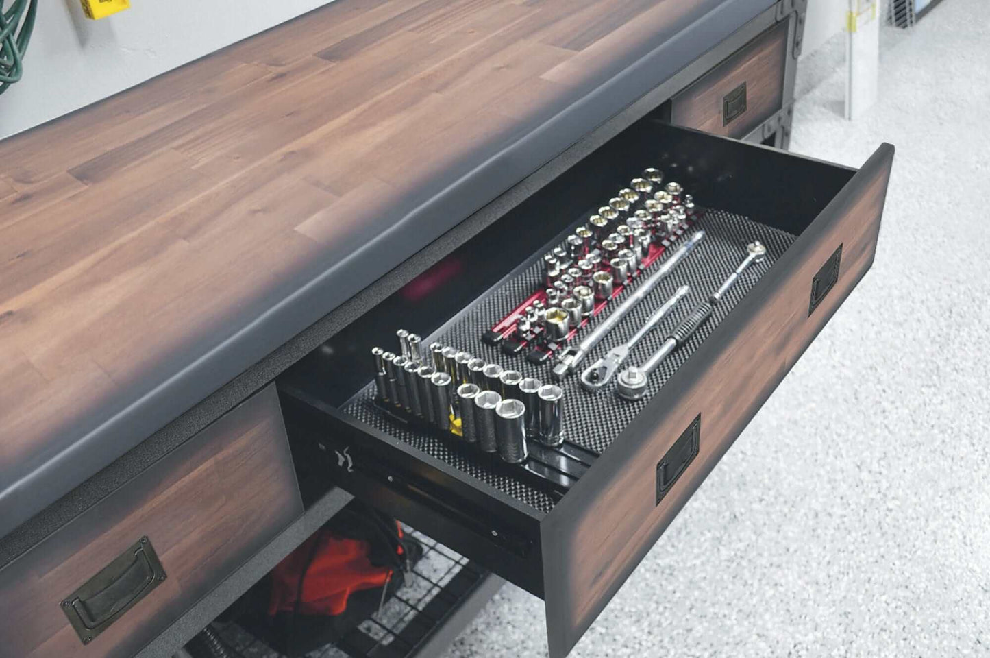 Drawer of a rolling workbench filled with organized tools and socket sets, showcasing storage efficiency.