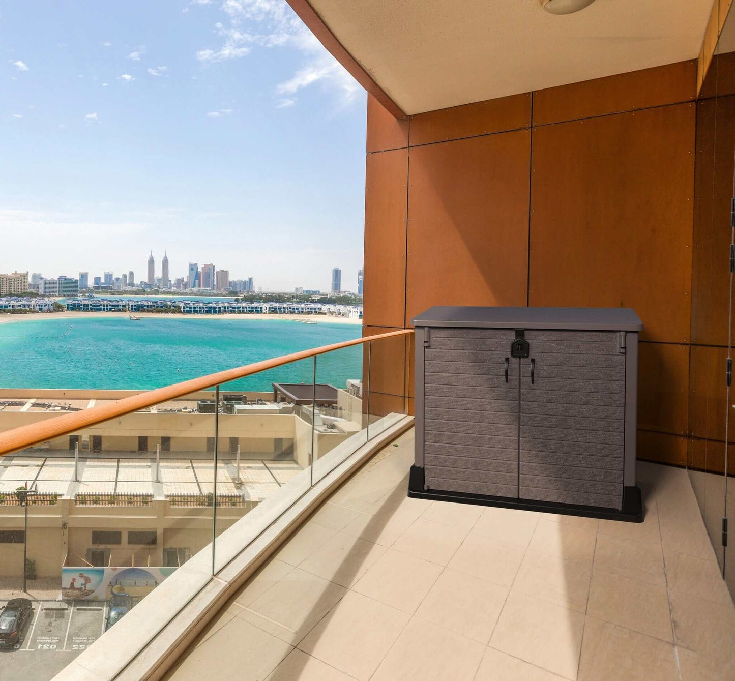 Duramax Storeaway 850L brown garden shed on a balcony with a scenic view of the city and waterfront.