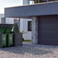 Stylish outdoor storage shed with two green bins, positioned by a modern house and garden.