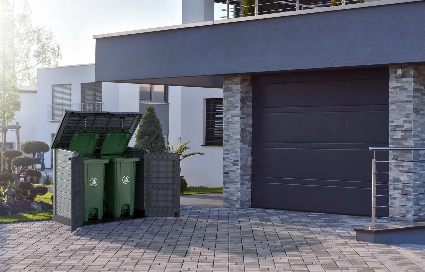 Stylish outdoor storage shed with two green bins, positioned by a modern house and garden.