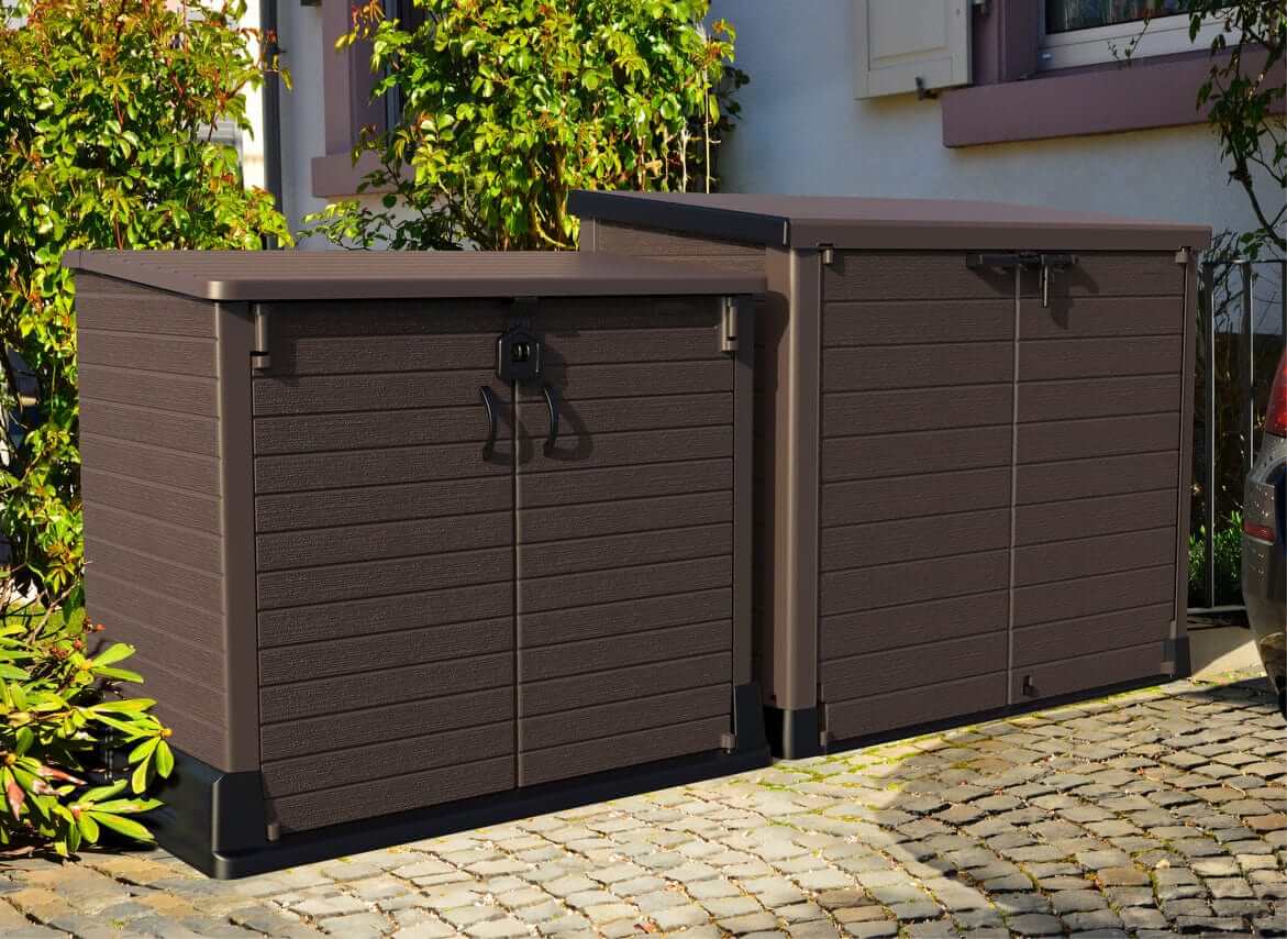 Duramax Storeaway Flat Lid 1200L Brown storage sheds in a garden setting, ideal for outdoor storage solutions.