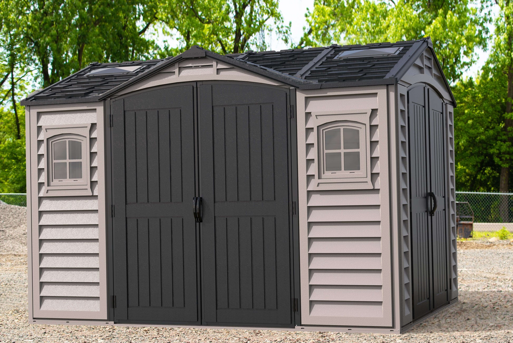 Duramax Vinyl Shed 10.5 x 8 Apex Pro with double doors and windows amidst a green outdoor setting.