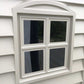 Close-up of a white vinyl window with four panes on the Duramax StoreMate Plus 6x6 shed.