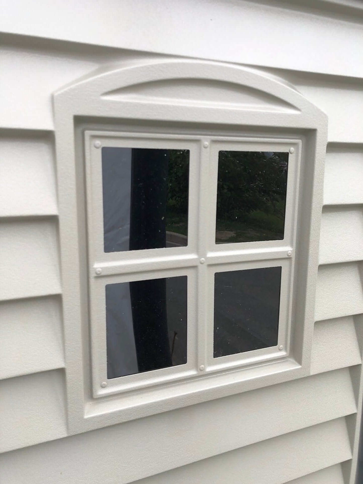 Close-up of a white vinyl window with four panes on the Duramax StoreMate Plus 6x6 shed.