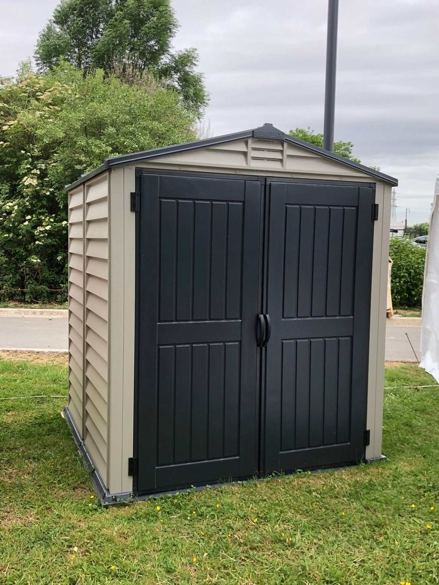 Duramax Vinyl Shed 6x6 StoreMate Plus with double doors in a grassy area.