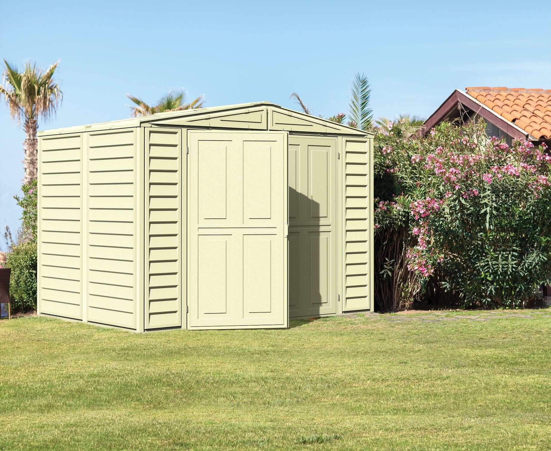 Duramax Vinyl Shed 8x6 DuraMate in a backyard setting with greenery around.