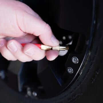 Hand using Air Drop inflator to add air to a tire, showcasing the product's convenience and efficiency.