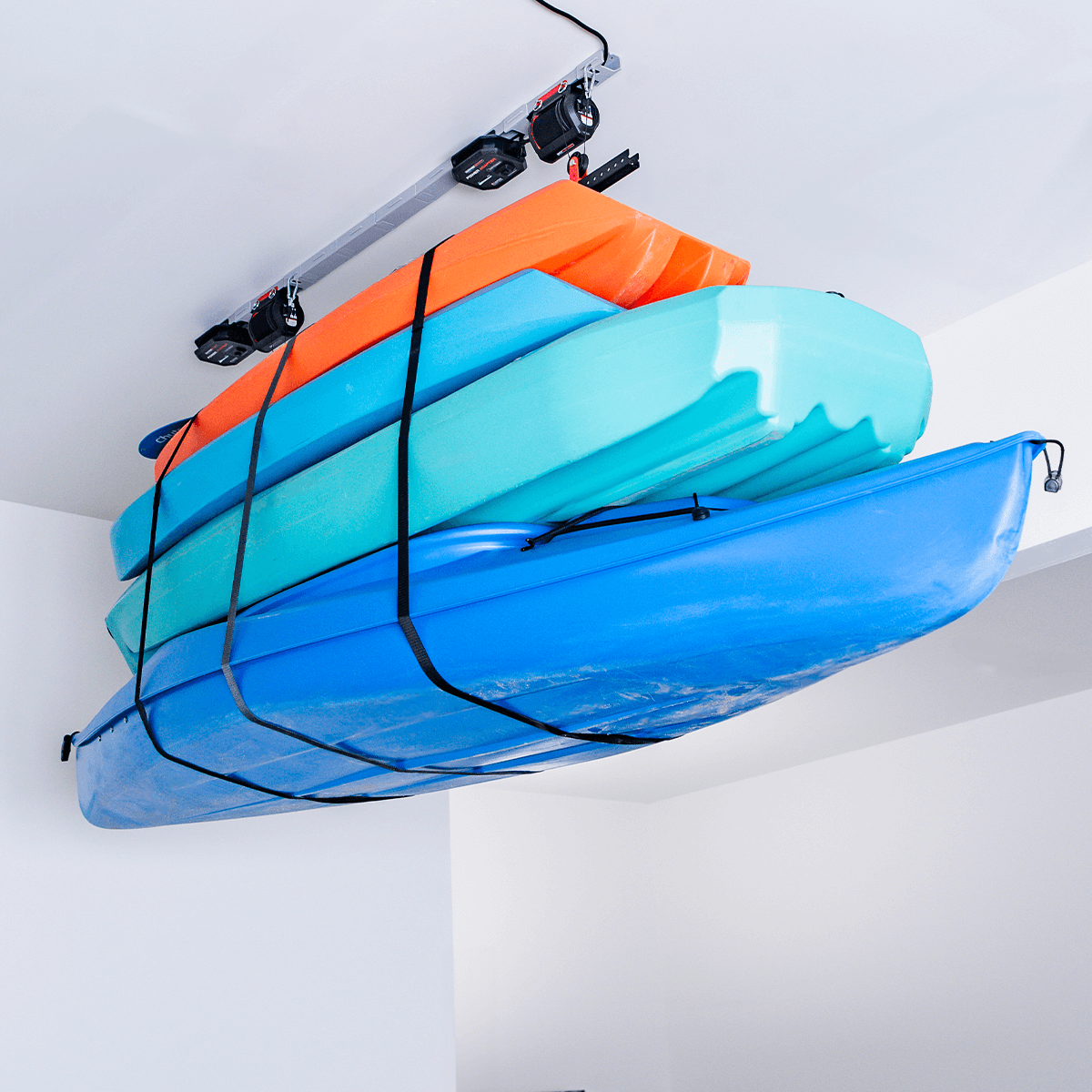 Motorized garage storage lift holding stacked kayaks, maximizing space and making heavy lifting easy.