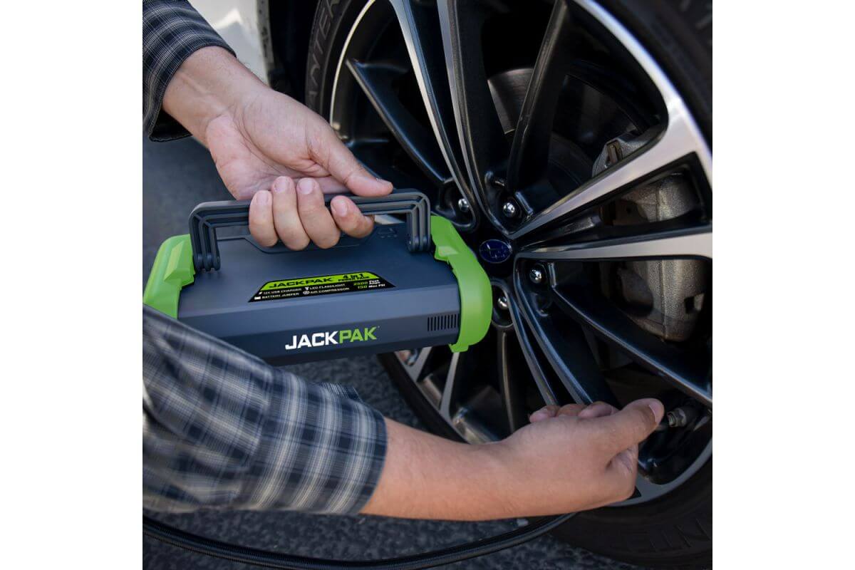 Person using JackPak ULTRA2500A jump starter and air compressor on a car tire.