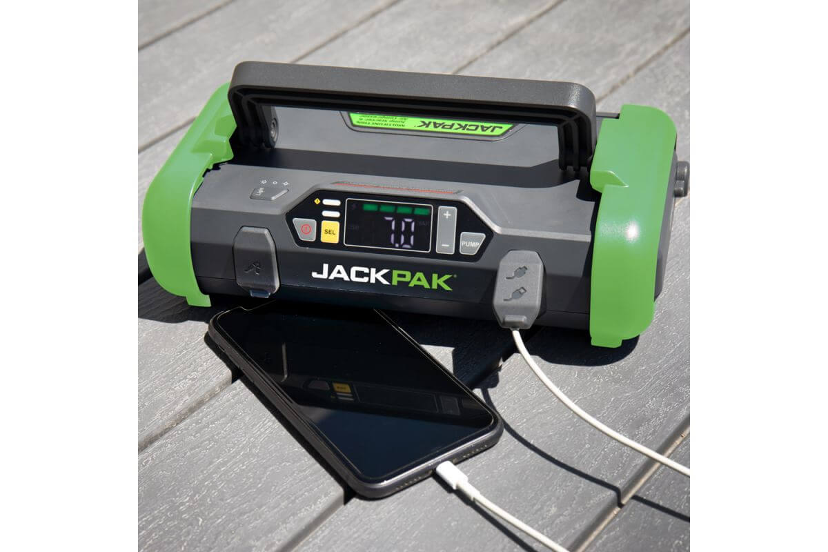 JackPak ULTRA2500A jump starter and air compressor charging a smartphone on a wooden surface.