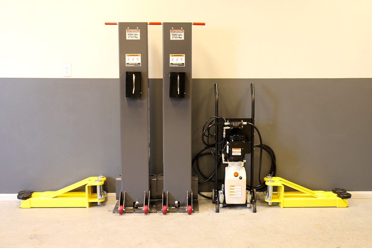 MaxJax M7K Portable Car Lift with cylinders and hydraulic pump in a garage setting.