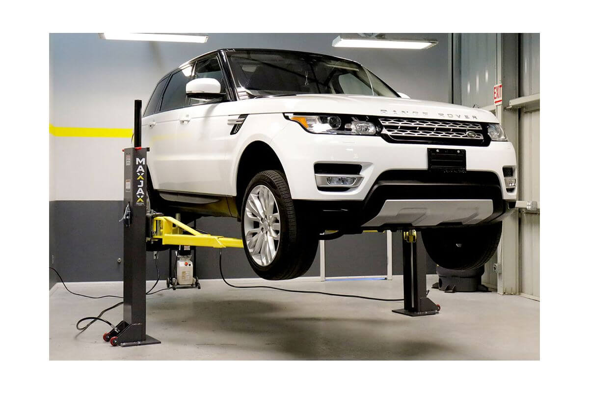 White SUV lifted by MaxJax M7K portable 2 post car lift, showcasing advanced safety and engineering.