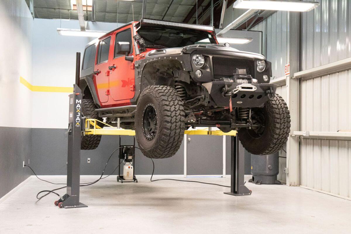 MaxJax M7K 2 Post Car Lift with a lifted black and red Jeep in an auto shop setting.