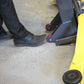 Foot activating MaxJax M7K 2 post car lift on a garage floor, showcasing safety and ease of use.