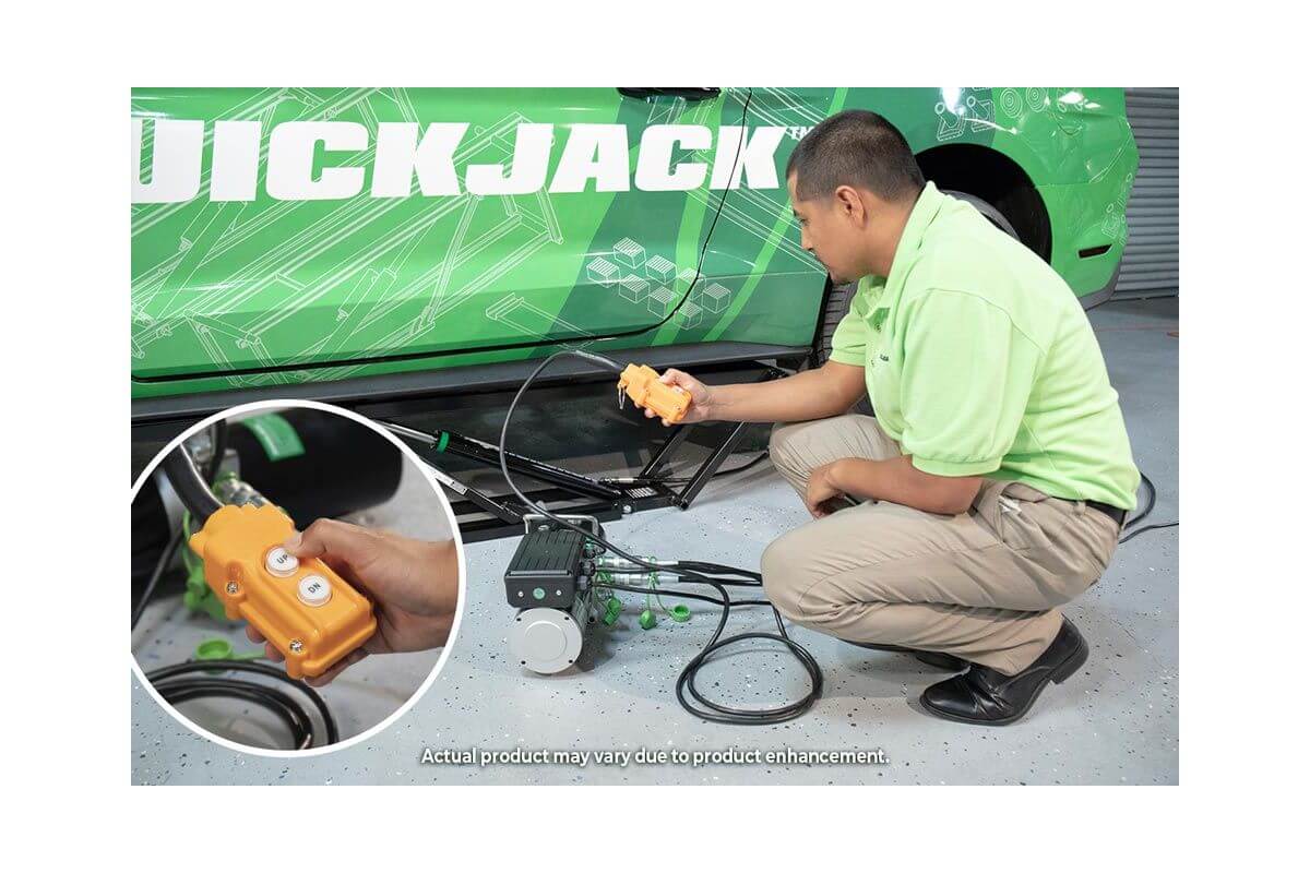 Man using QuickJack 5000TL portable car lift remote control beside the lift system.