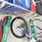 Heavy-duty wall shelves storing bikes and accessories in a garage, showcasing their 500-pound capacity and hooks for organization.