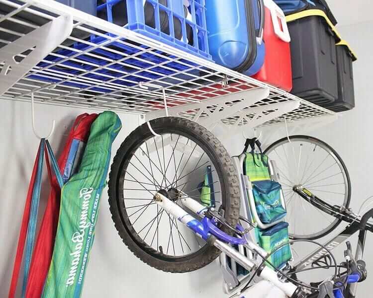 Heavy-duty wall shelves storing bikes and accessories in a garage, showcasing their 500-pound capacity and hooks for organization.