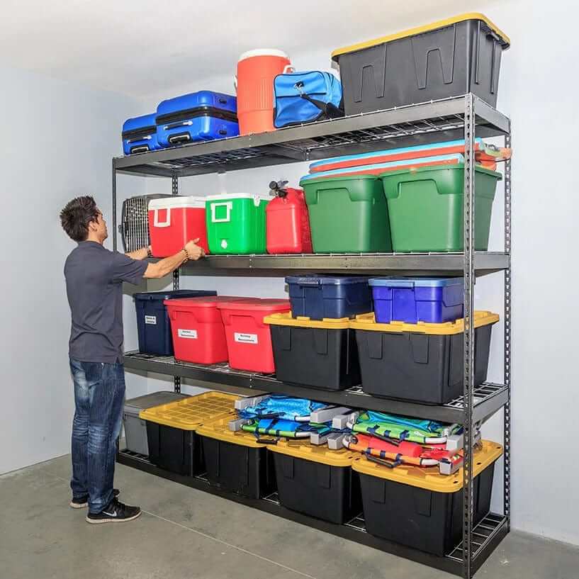 Man organizing colorful storage bins on heavy-duty garage shelving unit.