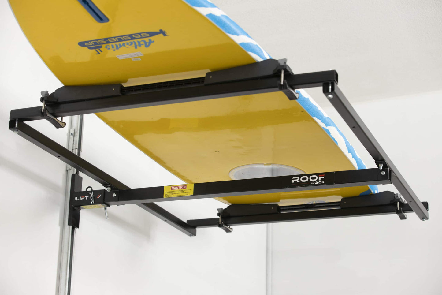 Motorized overhead storage lift by Top Shelf, holding a yellow surfboard securely in a garage.